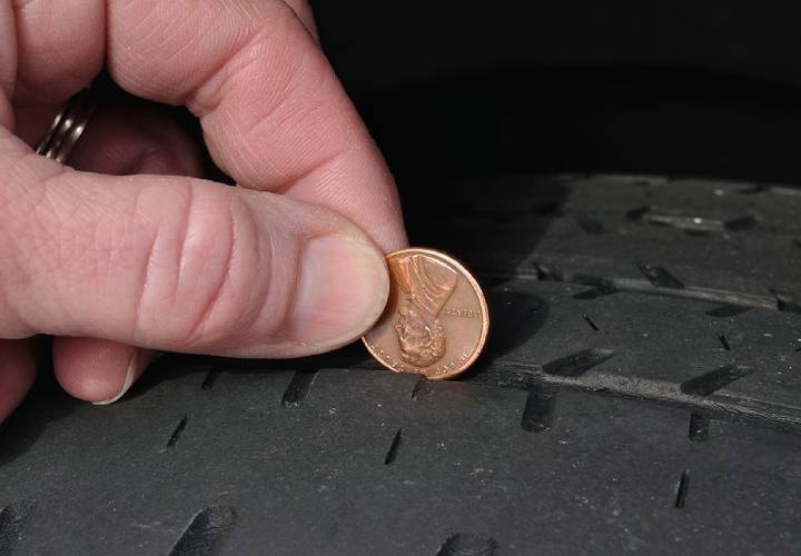 Inspecting The Wear Of A Balding Tire Tread Using a Penny