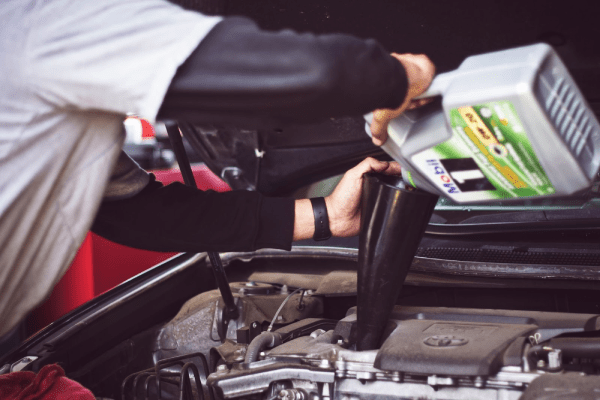 mechanic pouring engine oil