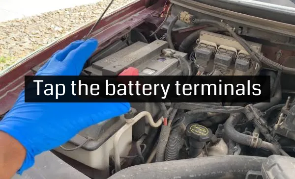 man tapping car battery terminals